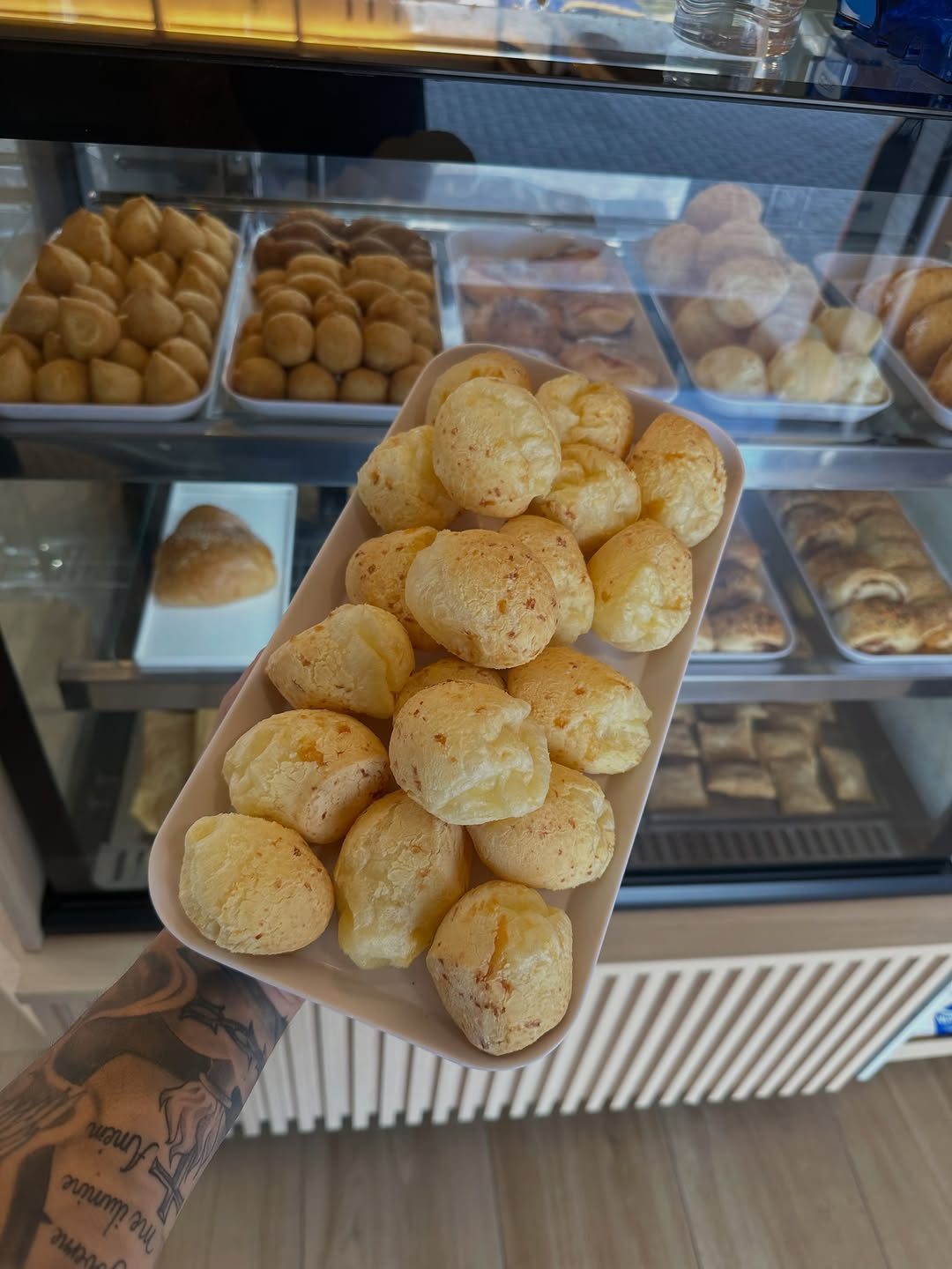 Bandeja de pães de queijo apresentada em frente à vitrine da panificadora