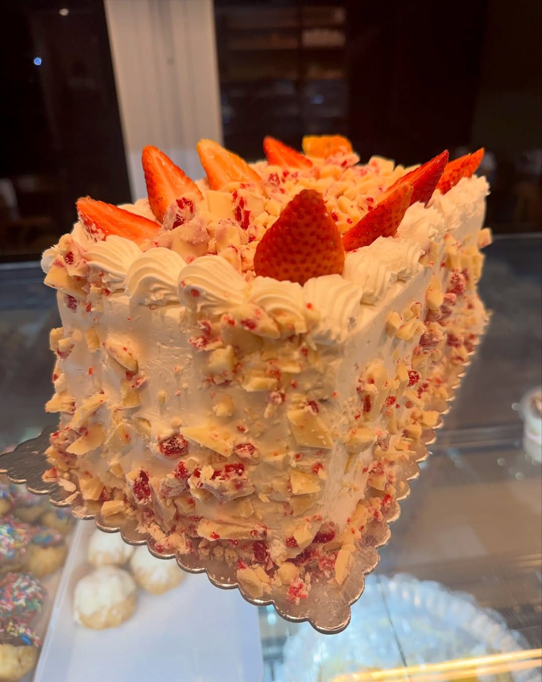 Bolo da Natal decorado com creme e morangos, sobre a vitrine da confeitaria
